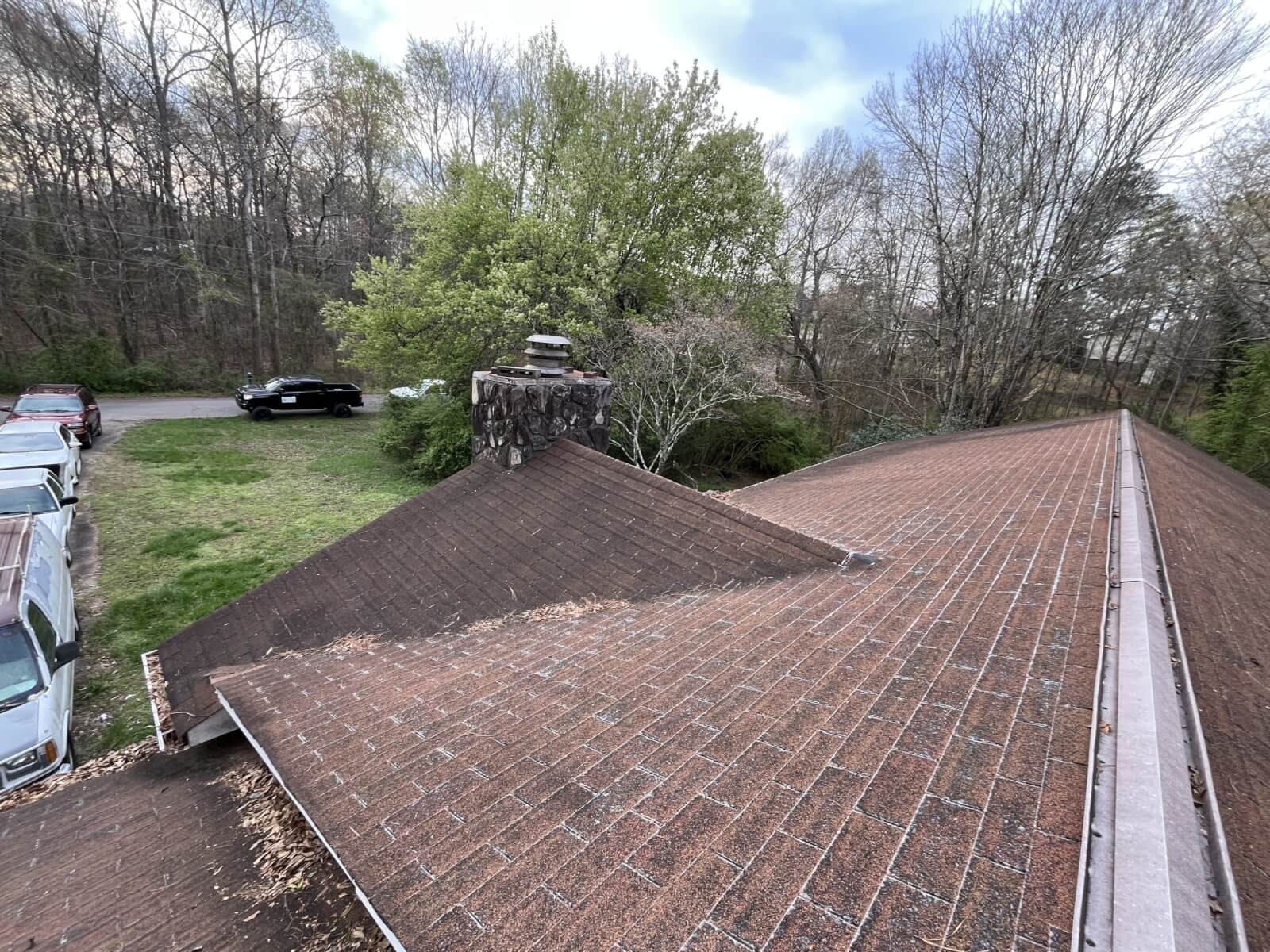 Worn, algae-streaked shingle roof on an Upstate SC home before replacement, with an aging chimney and vent caps